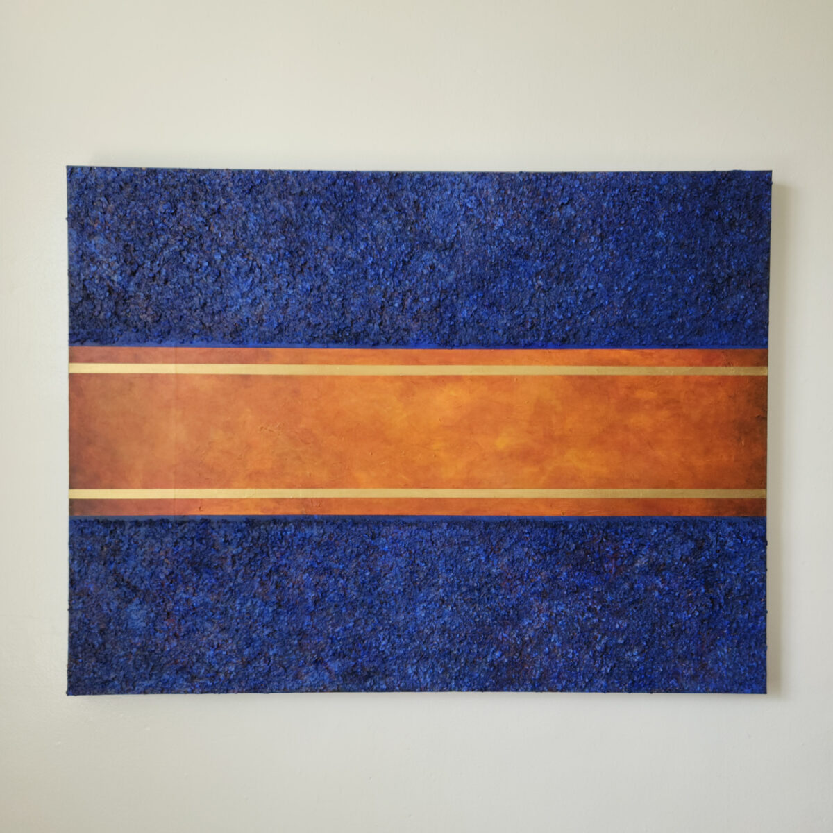 Mixed Media art. Three sections total. top and bottom are blue textured sections. middle is aged orange with two lines of gold near top and bottom.